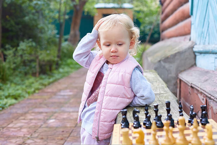 Child confused looking at chess board